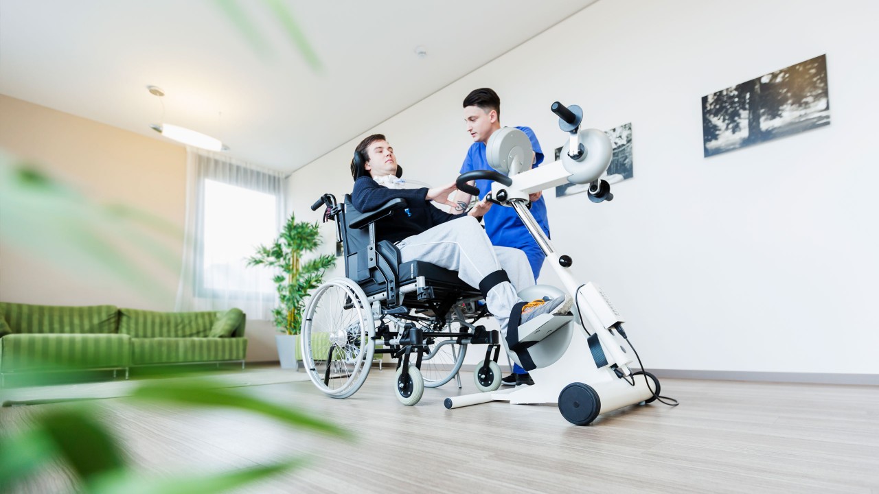 Patient im Rollstuhl trainiert an Fitnessgerät